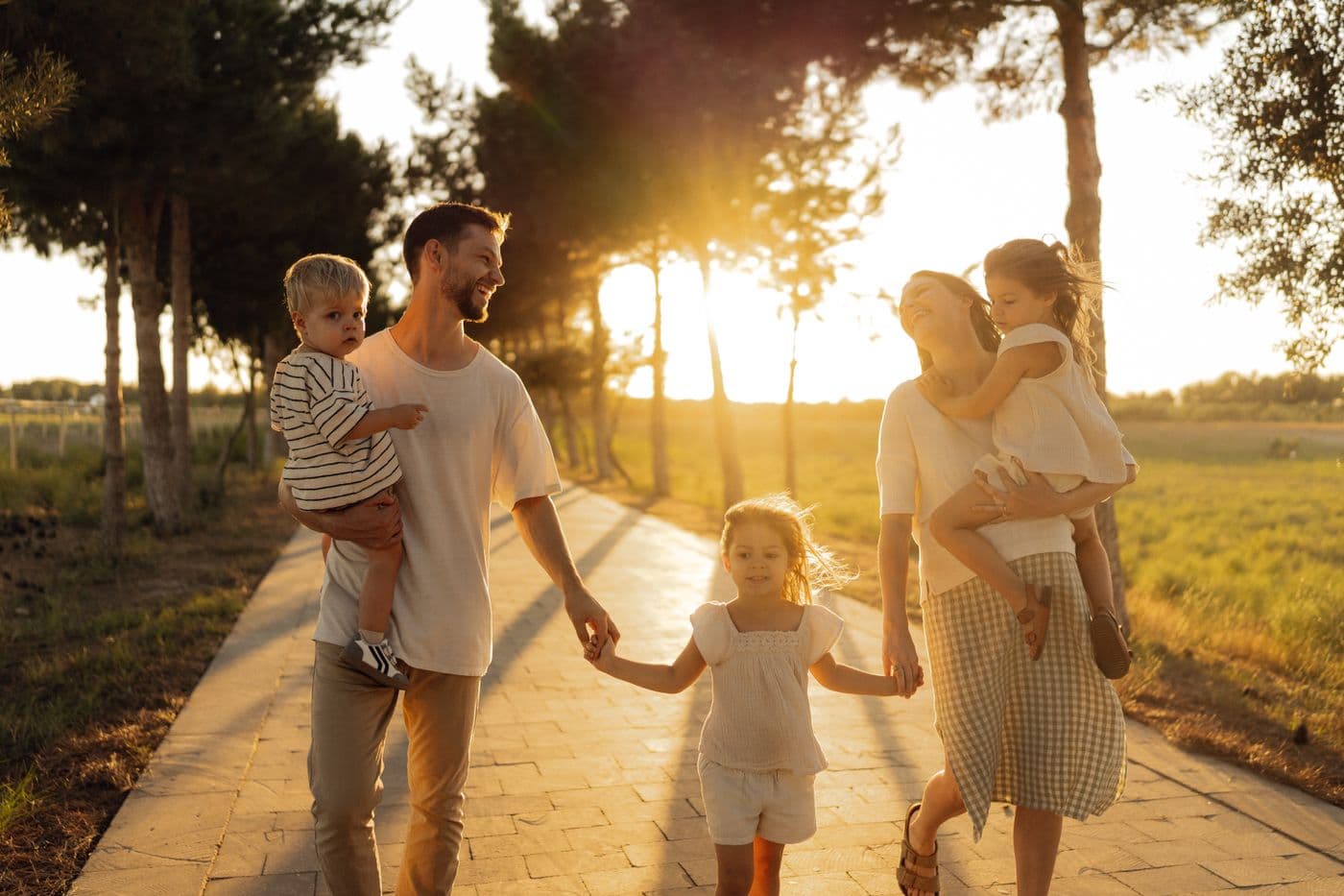 A family walking together along a sunlit tree-lined path